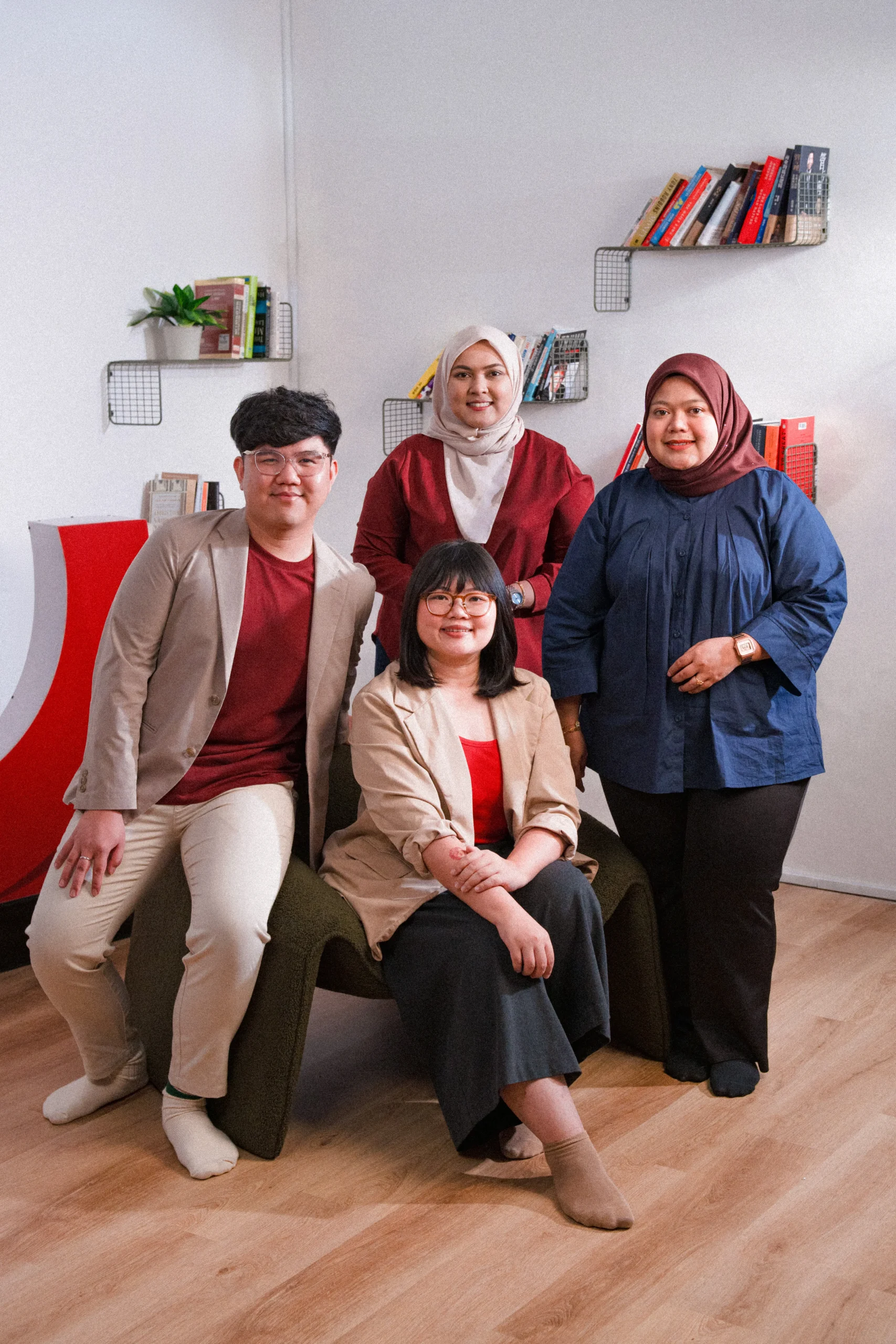 A group of four professionals posing together in a modern office setting, showcasing diversity and collaboration.